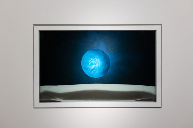 In 2011, NASA discovered the planet Kepler-22b through their Space Telescope. Kepler-22b is the first known planet (apart from Earth) to have the necessary conditions for sustaining human life, including the existence of water in liquid form on the planet’s surface. Pratchaya Phinthong’s artwork visualises Kepler-22b through a movable window, which, when rotated, dissolves and reconstitutes the landscape of sand, air and water (elements necessary for all forms of life). Fittingly, the artwork is named after a universal solvent (typically spelt ‘alkahest’), which in theory, is able to reduce every compound to its base elements.